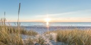 Een ondergaande zon vanaf de duinen met uitzicht op zee